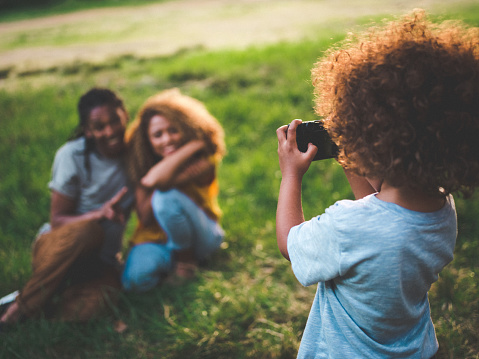 Happy african-american couple posing for a photo that their young curly haired son is taking of them