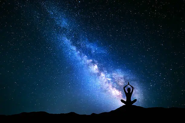 Photo of Milky Way and silhouette of a girl practicing yoga