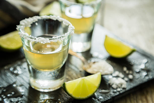 gold tequila-shots auf rustikalen holz-hintergrund - tequila shot tequila salt lemon stock-fotos und bilder