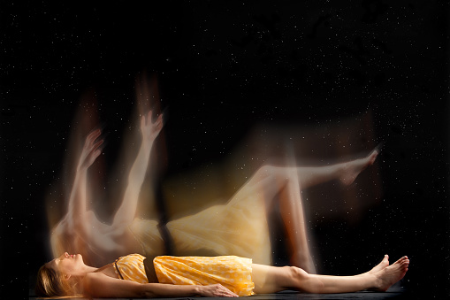 A concept image of a woman's spirit falling into tthe starry sky as she drifts to sleep.