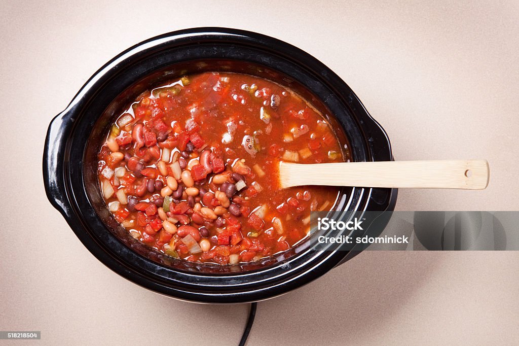 Overhead Vegetarian Chili In Slow Cooker An overhead view of vegetarian chili with a spoon in a slow cooker. Crock Pot Stock Photo