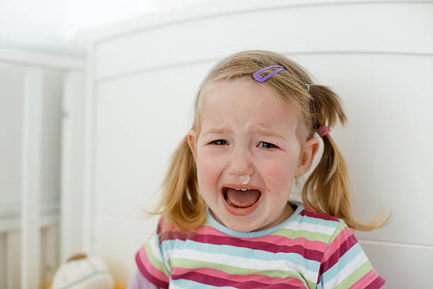 Crying little toddler, having a tantrum Crying little toddler, having a tantrum during a terrible two phase, raging in her crib. Childhood, growing up, developmental phase and parent patience concept. sneezing photos stock pictures, royalty-free photos & images