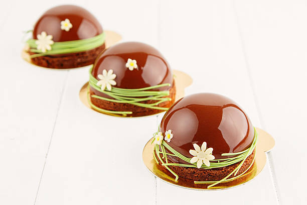 French mousse cake covered with chocolate glaze on white background. Modern european cake pastry foe Easter. Shallow focus