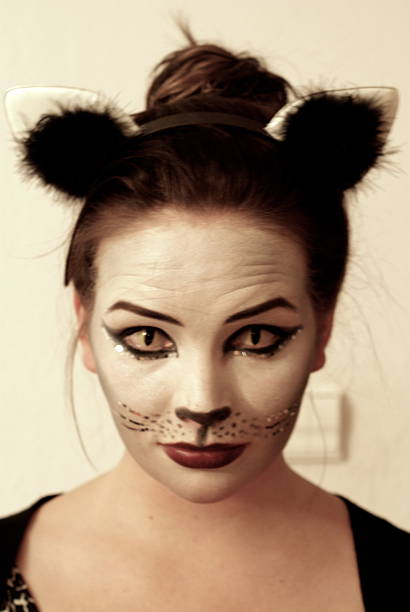 Halloween Cat Girl in Cat disguise with cat contact lenses, kitten ears, looks funny cat face paint stock pictures, royalty-free photos & images