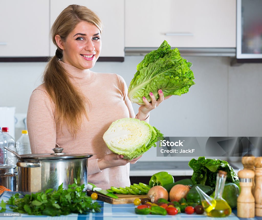 Portrait of smiling girl with lettuce indoors Portrait of adult girl with vegetables at kitchen table 25-29 Years Stock Photo