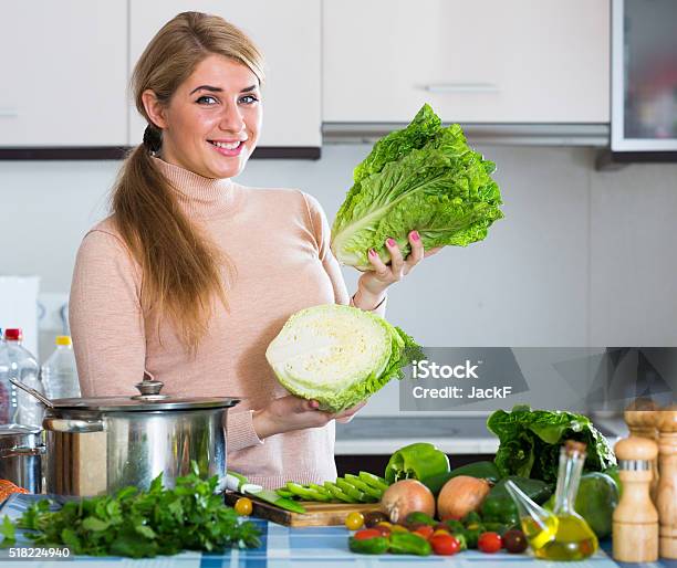 Portrait Of Smiling Girl With Lettuce Indoors Stock Photo - Download Image Now - 25-29 Years, Adult, Apartment