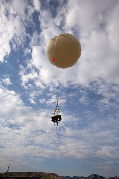 Part of a five year long national air quality project, a tethered balloon (able to carry 62 lbs.) and air testing payload ascends into the Golden, Colorado skies and relays meteorological (barometric pressure,wind speed,etc), pollution and emissions data (NO2, ozone, etc.) to a mobile ground station located on the State of Colorado property on the South Table Mountain. The front range of the Rocky Mountains stand in the background.