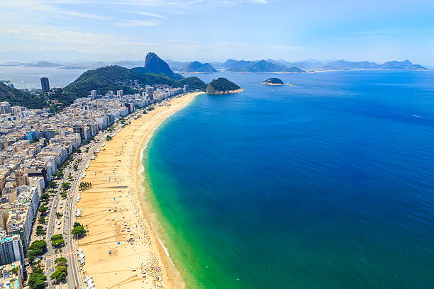 Aerial View of the Copacabana Beach in Rio de Janeiro Aerial view of the Copacabana Beach in Rio de Janeiro on a summer day, full of people enjoying themselves on it's clear blue water. One of the most famous beaches in the world next to the Ipanema Beach, Copacabana is widely visited by tourists from all around the world. copacabana stock pictures, royalty-free photos & images