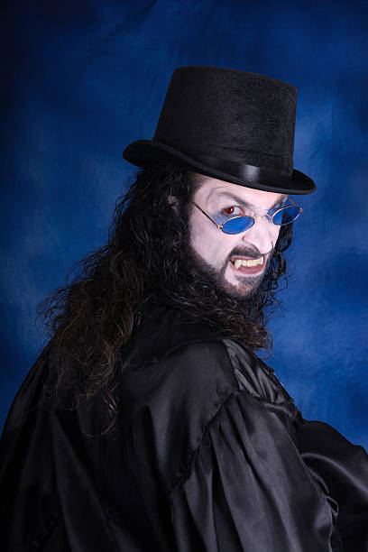 handsome gothic vampire with long black hair at the bottom of the wooden door of his castle