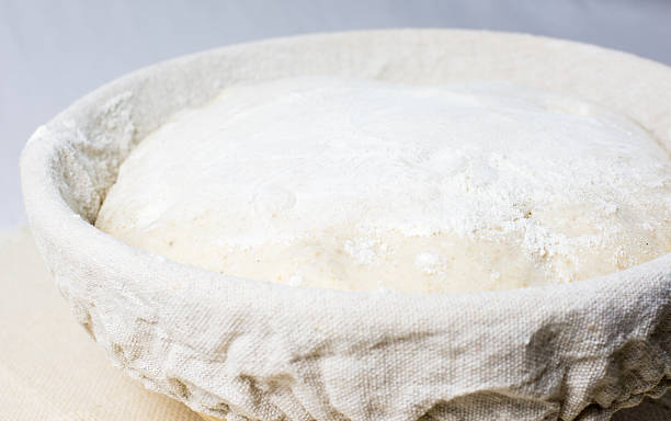 istock Bread dough proofing in linen cloth lined banneton 518248894