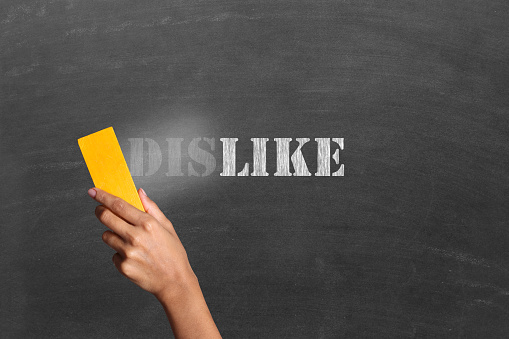 Changing word Dislike into Like. Close-up of a person hand holding duster and cleaning blackboard written the word 