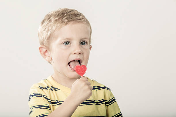istock Little Boy Licking a Heart Shaped Lollipop 518249882