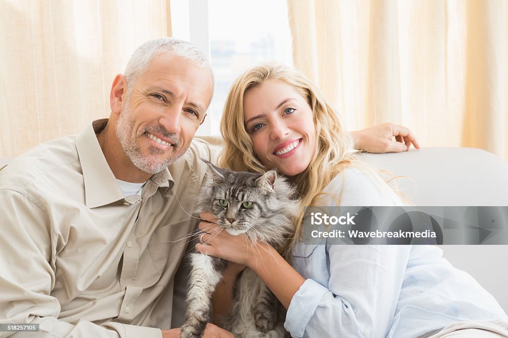 Happy couple with pet cat on sofa Happy couple with pet cat on sofa at home in the living room 20-29 Years Stock Photo