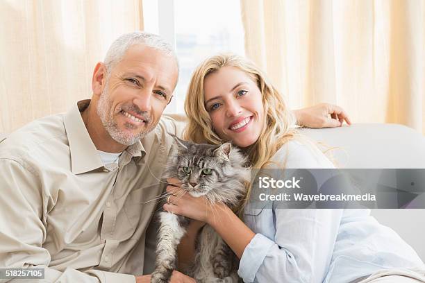 Happy Couple With Pet Cat On Sofa Stock Photo - Download Image Now - 20-29 Years, 25-29 Years, 40-49 Years