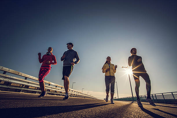 istock Below view of young smiling people running on a road. 518257832