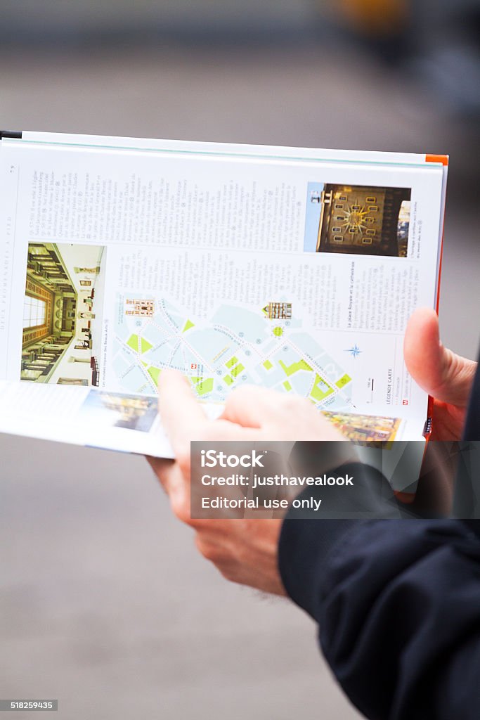 Guidebook of Brussels in hands Brussels, Belgium - August 28, 2014: Capture of young male caucasian tourist's hands holding guidebook of Brussels. Man is standing at square Grand Sablon in summer. Belgium Stock Photo