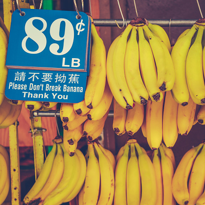 Retro Photo Of Bananas Hanging In A Market Stall In Chinatown With Badly Translated Sign