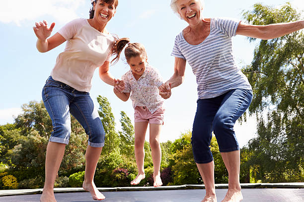 abuela, granddaughter y madre saltando sobre trampolín - trampolín artículos deportivos fotografías e imágenes de stock