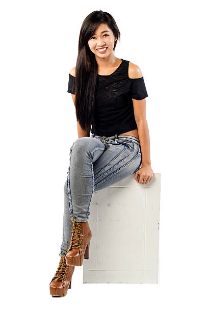 istock Young lady wearing jeans sitting on a white box 518262629