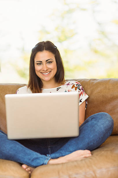 istock Pretty brunette relaxing on couch with laptop 518263579
