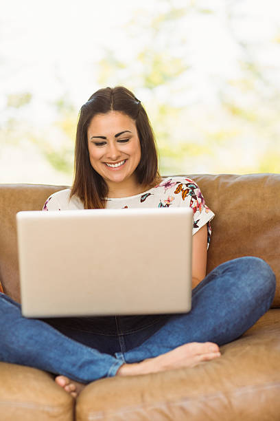 istock Pretty brunette relaxing on couch with laptop 518263581