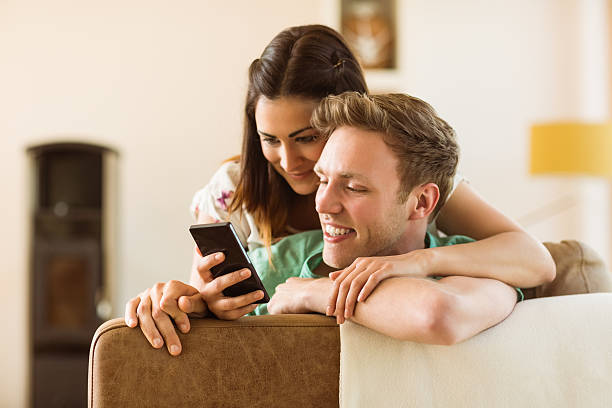 istock Cute couple looking at smartphone on couch 518263625