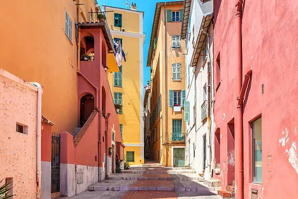 Narrow street among old colorful houses in Menton, France.