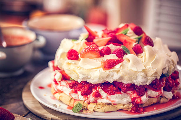 Delicious Berry Pavlova Cake with Strawberries and Raspberries Delicious Berry Pavlova Cake with fresh strawberries, raspberries, mint leaves and whipped cream. pavlova stock pictures, royalty-free photos & images