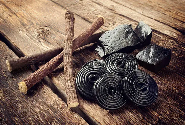 Production steps of licorice, roots, pure blocks and candy on wooden table