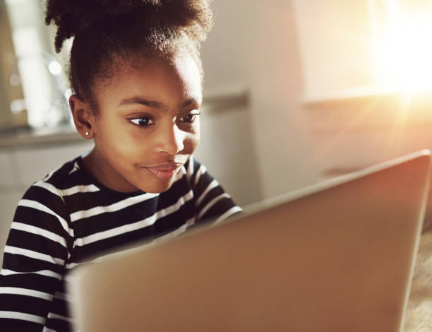 istock Trendy little girl using a laptop at home 518274496