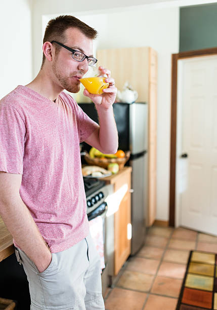 istock man standing drinking orange juice for breakfast 518274700