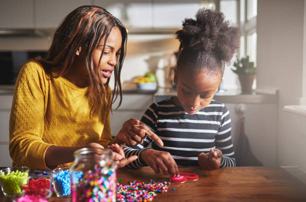 istock Parent pointing at beads with girl at table 518283292