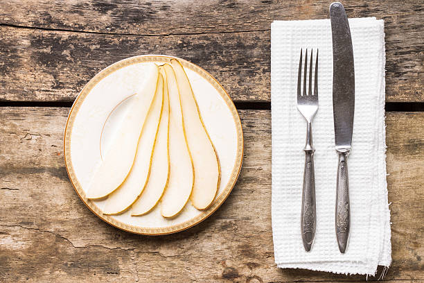 istock Sliced pear on saucer with silverware on the table 518284146
