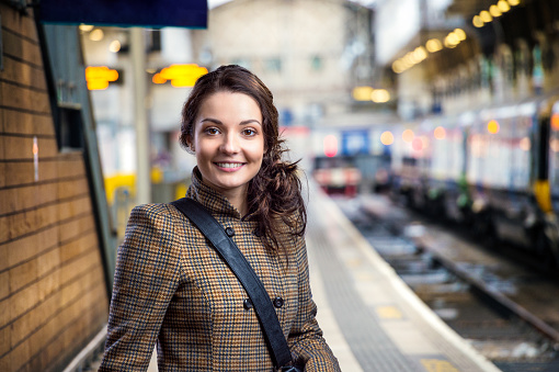 Young woman in checked brown winter coat waiting on train station