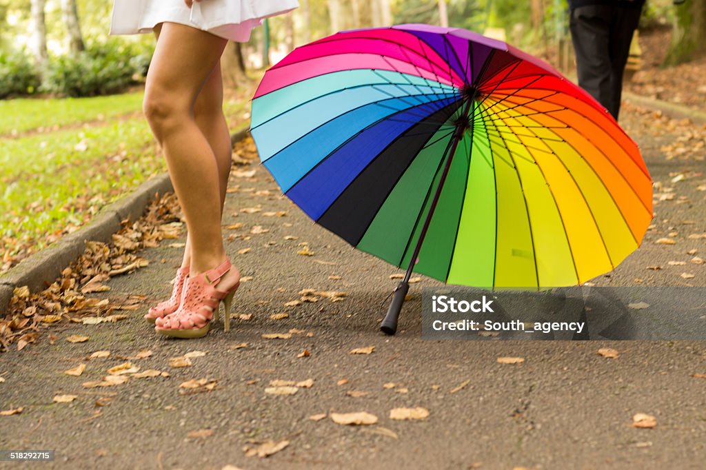 Prepared for the rain Young woman with beautiful legs standing in elegant dress. She is wearing glamorous high heels. She have a colorful umbrella. Adult Stock Photo