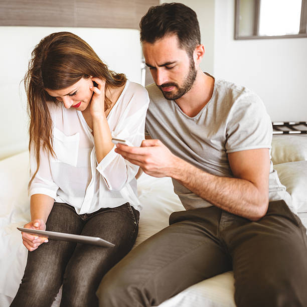 istock couple using a mobile phone sitting on the bed 518298467