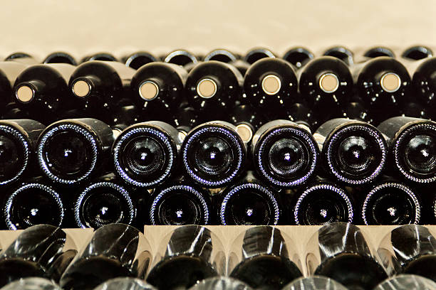 Red wine bottles stowed in winery for aging process.