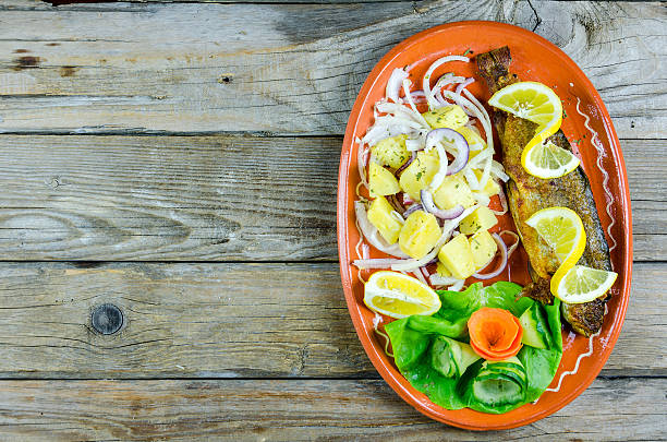 Trout with vegetables on a clay plate standing on an old wooden table
