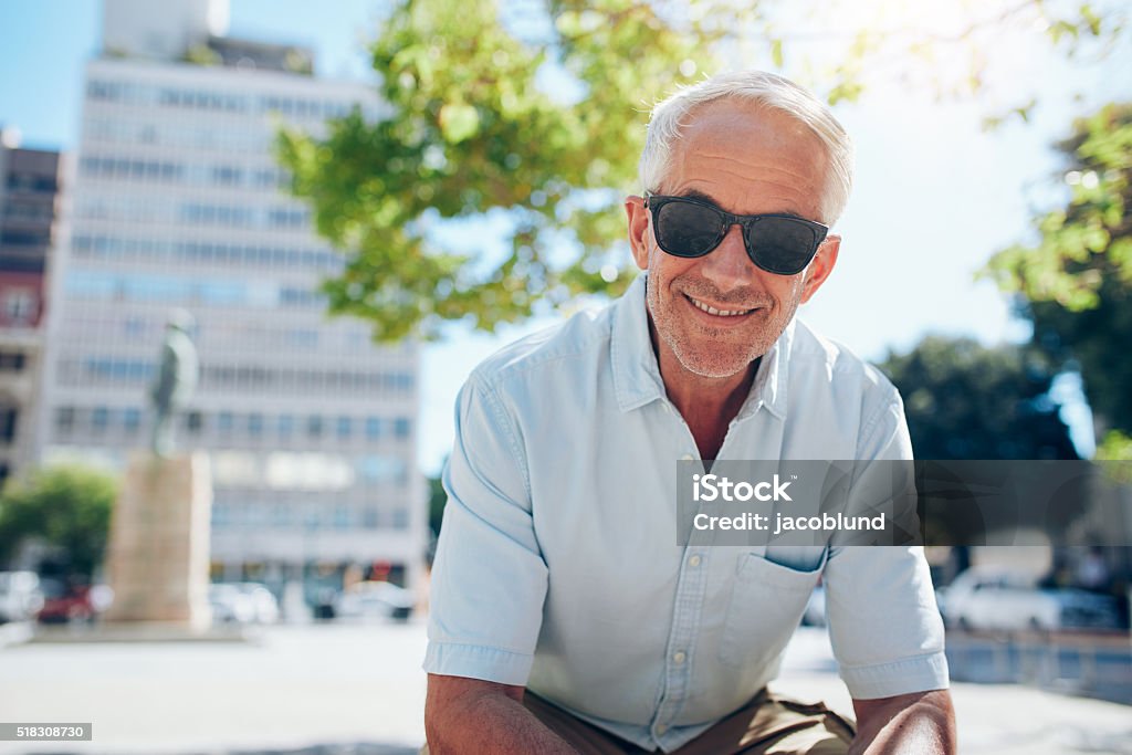 Glücklich leitender Mann sitzt im Freien in der Stadt - Lizenzfrei Sonnenbrille Stock-Foto