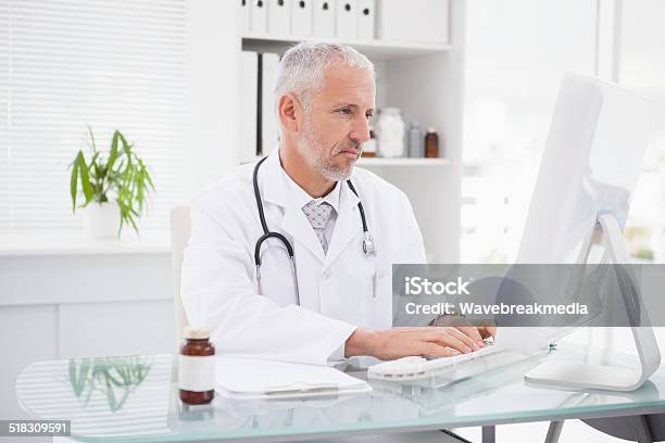 Happy Doctor Typing On Keyboard Stock Photo - Download Image Now - Doctor, Cheerful, Computer Monitor