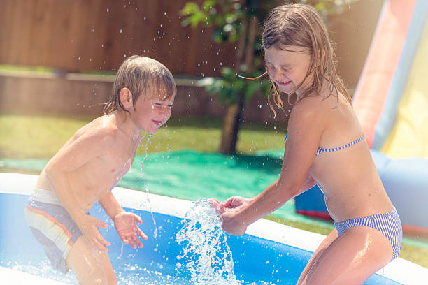 istock Brother and sister playing in an inflatable pool 518325990