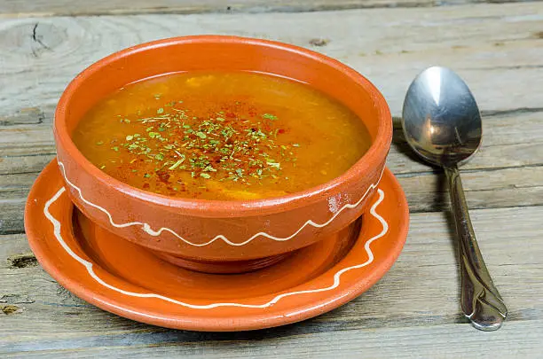 fish soup into a clay plate at wooden board or table