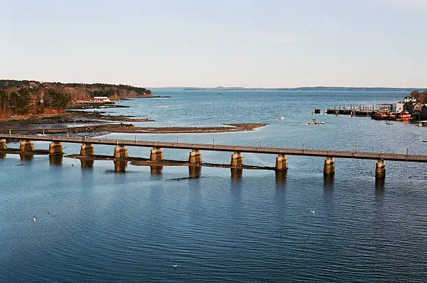 WWII memorial Footbridge at the mouth Passagassakaweag River before Belfast Bay at lowtide. in the distance the blue hills of Downeast Maine peek over the horizon on a clear winter day