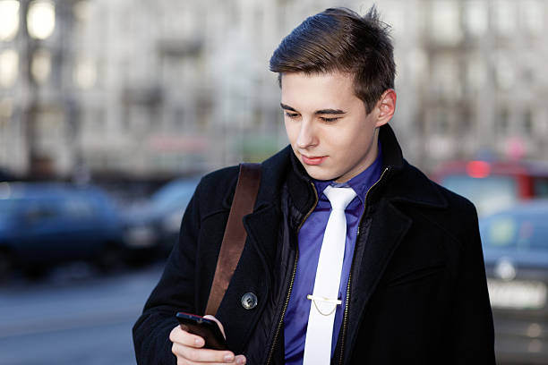 istock Classic dressed smiling young man with a mobile phone. 518336838