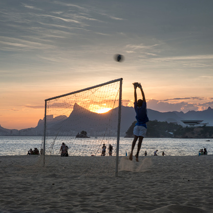 Niteroi, Rio de Janeiro, Brazil - December 28, 2014: Young boy playing beach football as a goal keeper and saving a goal at Icarai Beach with Rio de Janeiro on the background.