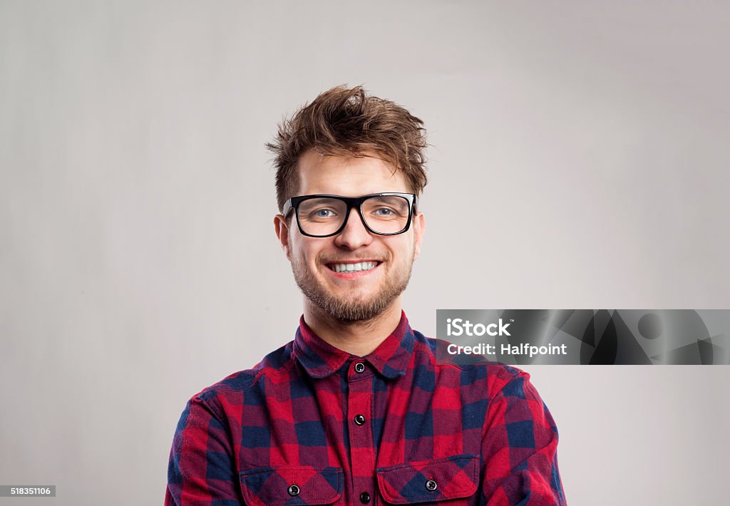Man in checked shirt and eyeglasses against gray background. Hipster man in red checked shirt and eyeglasses. Studio shot on gray background Men Stock Photo