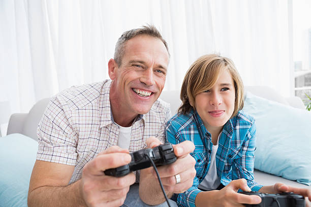 istock Son and father playing video games together on the couch 518352711