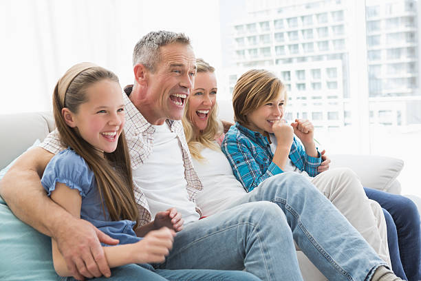 istock Excited family watching television on sofa 518352727