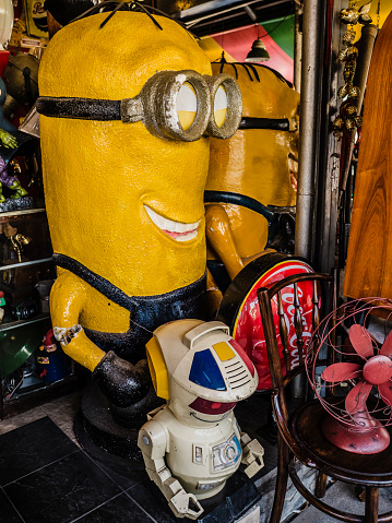 Bangkok, Thailand - February 14, 2016: A shop near Chatuchak market in Bangkok selling assorted vintage objects. among those a pair of statues of Minions and a robot