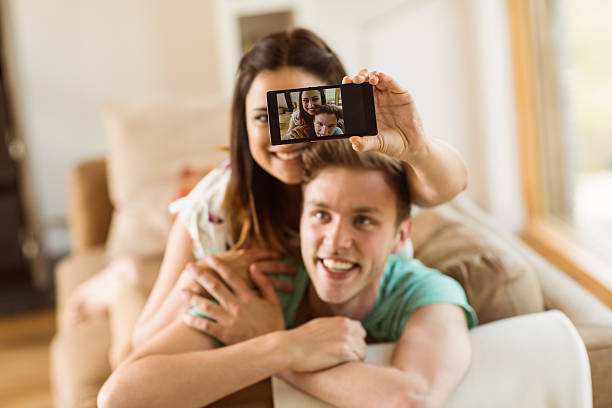 istock Cute couple taking a selfie on couch 518354993